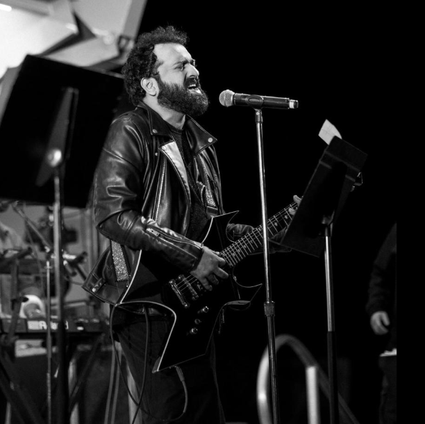 Sri Charan Pakala singing live on stage with guitar and microphone